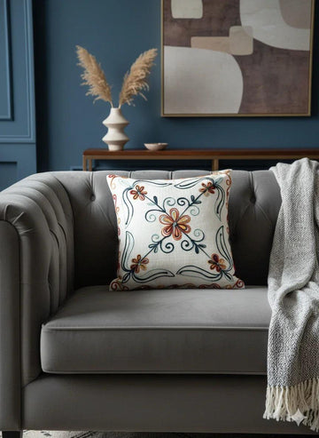 Floral embroidered throw pillow on gray tufted sofa, cozy living room decor with abstract wall art