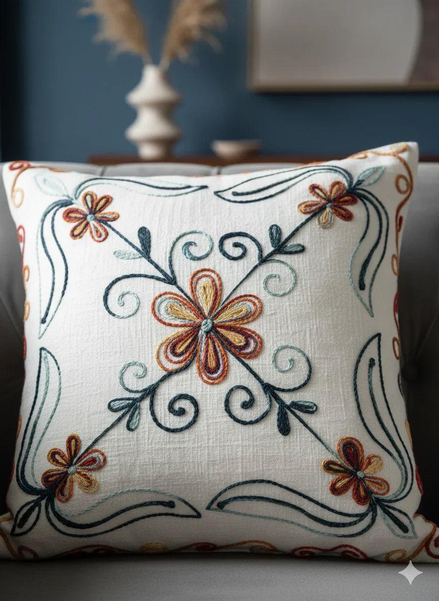 Embroidered floral pillow with orange and teal flowers on cream fabric, decorative home accent