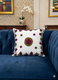 White floral embroidered cushion on blue velvet sofa, decorative home accent with red and gold motifs