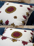 White throw pillow with red and gold floral embroidery, styled on blue sofa for home decor