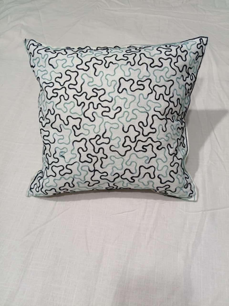 Abstract patterned throw pillow on gray sofa, modern living room decor with art and plant